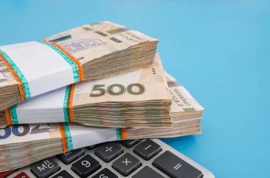 Hryvnia demetleri ve mavi arka planda bir hesap makinesi. İçinde 500 Hryvnia olan bir yığın. Çok para..
