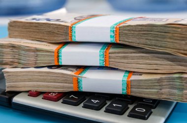 Hryvnia demetleri ve mavi arka planda bir hesap makinesi. İçinde 500 Hryvnia olan bir yığın. Çok para..