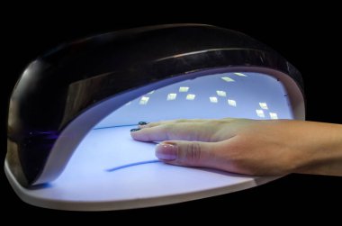 UV lambası jöle cilası manikür süreci. Salon prosedürü. Müşteri manikürü lambayla kurutuyor..