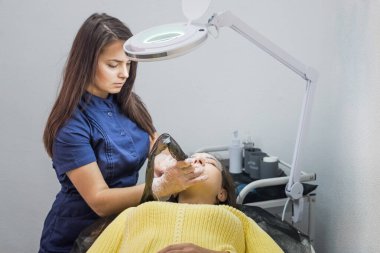 Kalıcı kaş makyajı sırasında salonda usta ve müşteri var. Kaş dövmesi, işlem. Usta tarafından kalıcı kaş makyajı için kullanılan aletler..