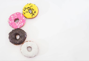 dört geleneksel Amerikan donutu çikolatalı, pembe, sarı, beyaz arkaplanda izole edilmiş beyaz krema ve şekerli. Uzayı kopyala Yukarıdan görüntüle.
