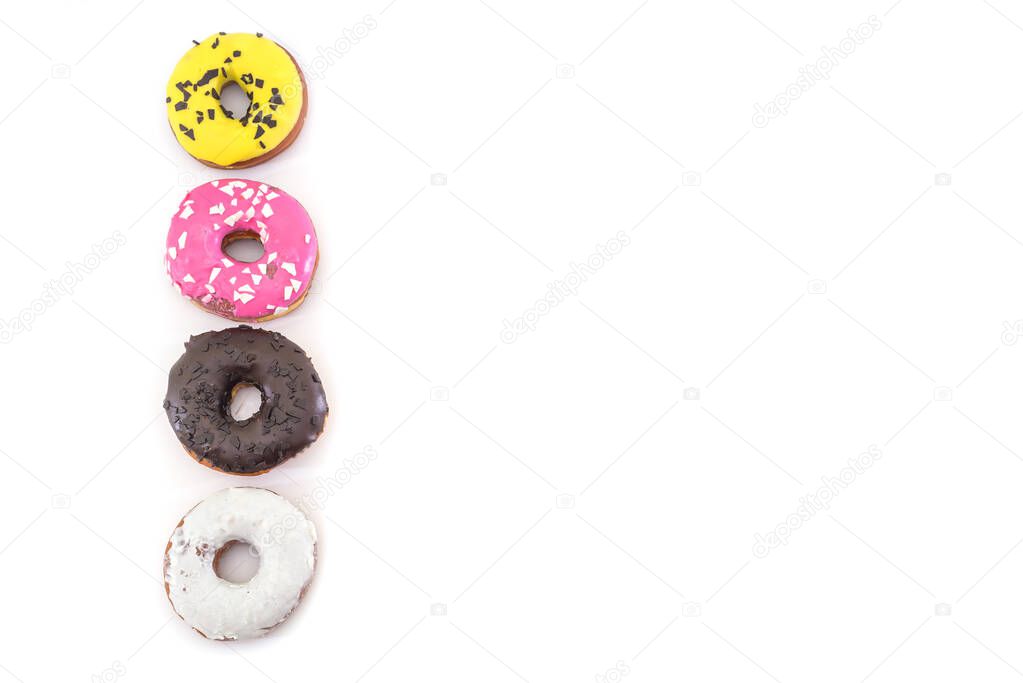 row of traditional American donuts with chocolate, pink, yellow, white icing and sprinkles isolated on white background. Copy space. Place for text.