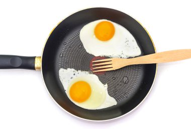 Kızartma tavasında çırpılmış yumurta ve beyaza izole edilmiş ahşap çatal. Yukarıdan görüntüle