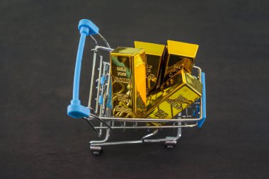 Siyah ahşap arka planda alışveriş arabasında altın külçeler. Yukarıdan görüntüle.