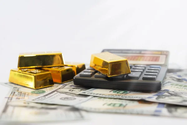 gold bars and calculator on the background of dollars. Side view.