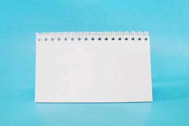 Mavi arkaplandaki boş beyaz not defteri. Boşluğu kopyala. Metin için yer.