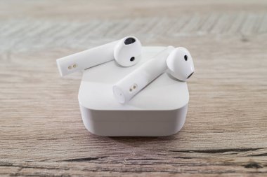 Beyaz kablosuz kulaklıklar ahşap bir masada bir kutuda..