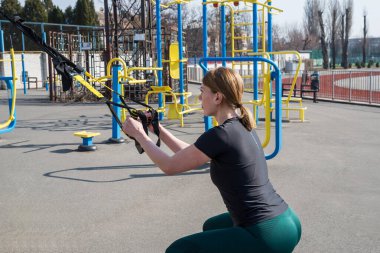 TRX kayışları egzersizi yapan genç ve güzel bir bayan eğitmen. Sağlıklı bir yaşam için her şey.