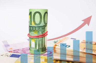 100 Euro ve Euro 'luk banknotları beyaza yatırmış. Kırmızı oklu finansal büyüme grafiği. Yakın plan..