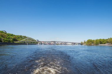 Kiev, Ukrayna - 11 Mayıs 2021: Kiev, Ukrayna 'daki Dinyeper Nehri' nden köprünün görüntüsü. Buharlı teknesi olan güzel bir manzara..