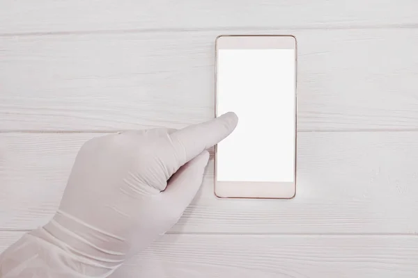 白い手袋の医者は白い空白の画面でスマートフォンに指に触れる 白い背景の上に隔離された スペースのコピー — ストック写真