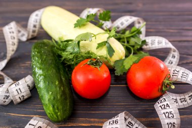 Çeşitli sebzeler ve ahşap bir arka planda mezura. Düz yatıyordu. Yukarıdan bak. Kilo verme, sağlıklı beslenme kavramı.