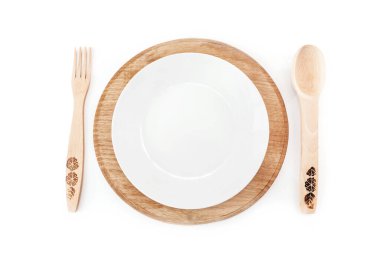 Boş tabak, tahta çatal ve kaşık beyaz arka planda izole edilmiş. Üst görünüm.