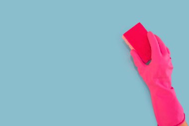 hand in a pink glove holds a washcloth isolated on a blue background. Copy space. Cleaning concept.