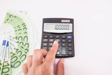 Bir elin yakın çekimi, bir hesap makinesiyle geliri hesaplar. Finansal konsept. Yukarıdan görüntüle.