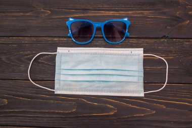 Ahşap arka planda güneş gözlüğü ve koruyucu tıbbi maske