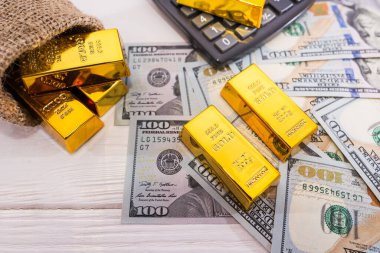 Dolarlı altın külçeler ve hesap makinesi. Zenginlik kavramı.