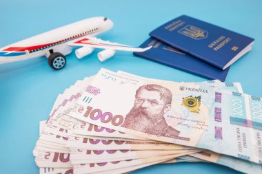 Mavi üzerinde Ukrayna pasaportu ve Hryvnia olan oyuncak uçak. Turizm konsepti, seyahat.