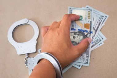 Ellerinde dolar banknotları olan elleri kelepçele. Rüşvetle kelepçelenmiş bir adam