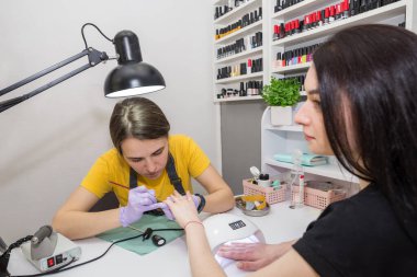 Usta bir kadın bir kuaförde müşterisi için oje sürüyor. El bakımı kavramı.