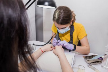 Kadın efendi müşteriye kuaförde manikür yaptırıyor. Çivi bakımı kavramı.