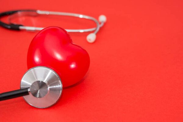 red heart and stethoscope on isolated red background with copy space. Health concept, heart disease.