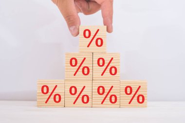 Faiz oranı finansal ve ipotek oranları kavramı. Elle yerleştirilen tahta küp bloğu üste yükseltiliyor ve simge yüzdesi sembolü yukarı doğru gösteriliyor