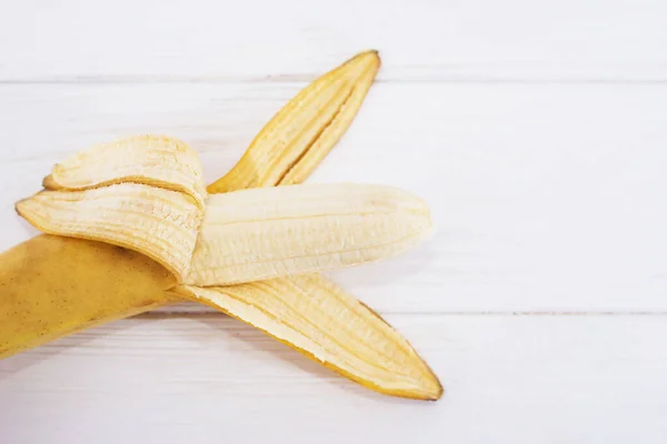 open banana on a white wooden background. Close-up.