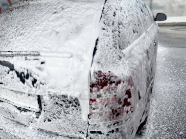 Otomobil yıkamada köpüklü bir arabanın yakın çekimi. Araba yıkama konsepti.