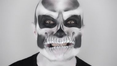 Korkunç cadılar bayramı iskelet makyajlı adam korkutmaya çalışıyor. Stüdyoda çekim. Gri arkaplan