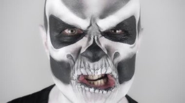 Korkunç cadılar bayramı iskelet makyajlı adam korkutmaya çalışıyor. Stüdyoda çekim. Gri arkaplan