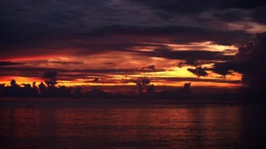 Kumsaldaki kara bulutların içinde renkli bir şafak. 