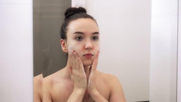 快乐迷人的年轻女人用洁白的泡沫洗脸 镜像中的特写映像 — 图库视频影像
