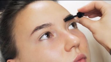 Makyöz bir kadına kaş tarıyor. İdeal formun oluşumu. Profesyonel güzellik hizmetleri..