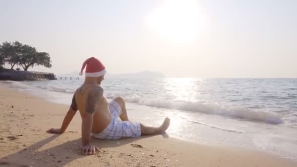 Ein Mann Sitzt Mit Nikolausmütze Sand Meer Frohes Neues Jahr — Stockvideo