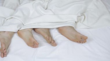 Genç, güzel ve sevgi dolu bir çift yorganın altında dans ediyor. Bacakları yakın çekim, üst manzara