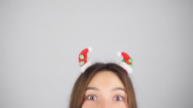 Saçında Noel süsü olan mutlu esmer kadın hava öpücüğü yolluyor. Hafif arkaplan.