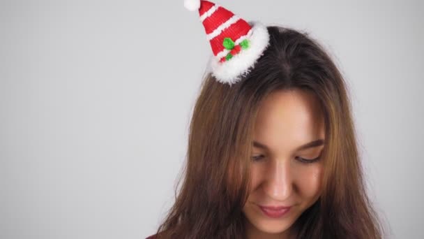 头发上挂着圣诞装饰品的快乐的黑发女人 这个女人害羞地抬起头笑了 背景浅 — 图库视频影像