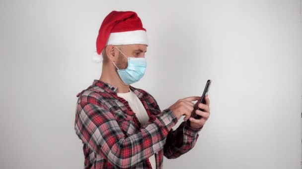 산타 모자를 쓴 남자가 인터넷으로 글을 읽고 뉴스를 보고 깜짝 놀란다. — 비디오