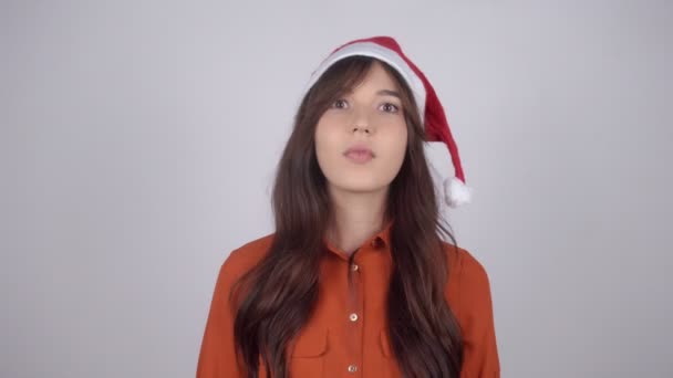 Noel Baba şapkalı güzel bir kadın tıbbi maske takıyor ve baş parmağını kaldırıyor. — Stok video