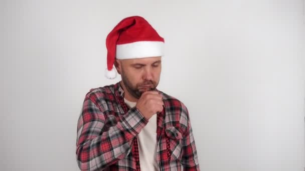Noel Baba şapkası takan bir adam öksürüyor ve tıbbi maske takıyor. — Stok video