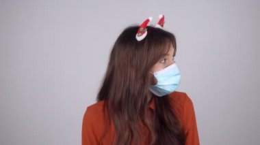 Saçında Noel süsleri olan güzel genç bir kadın etrafına bakar ve şşş hareketi gösterir. Yüksek kalite 4k görüntü