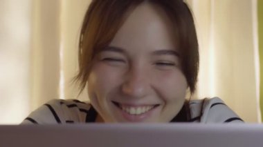 Genç bir kadın koronavirüsten kendini izole ederken evde otururken video konferans yapıyor. Kahve ve video içen bir kadın arkadaşlarıyla arıyor. Yüksek kalite 4k görüntü