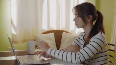 Genç ve güzel bir kadın bir netbook klavyesinde, dizüstü bilgisayarında daktilo kullanıyor. Coronavisur salgını, evde kal. Yüksek kalite 4k görüntü