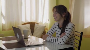 Genç bir kadın koronavirüsten kendini izole ederken evde otururken video konferans yapıyor. Kahve ve video içen bir kadın arkadaşlarıyla arıyor. Yüksek kalite 4k görüntü