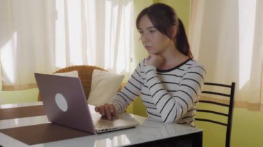 Genç ve güzel bir kadın bir netbook klavyesinde, dizüstü bilgisayarında daktilo kullanıyor. Coronavisur salgını, evde kal. Yüksek kalite 4k görüntü