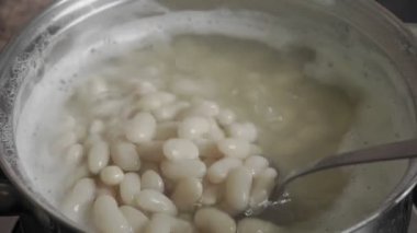Fasulye Pişirme Süreci beyaz fasulye tohumları bir tencerede kaynar su içinde. Yüksek kalite 4k görüntü