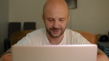 Evdeki kel sakallı adam video aracılığıyla iletişim kuruyor. Kilitli adam evden çalışıyor. Tam HD görüntüler