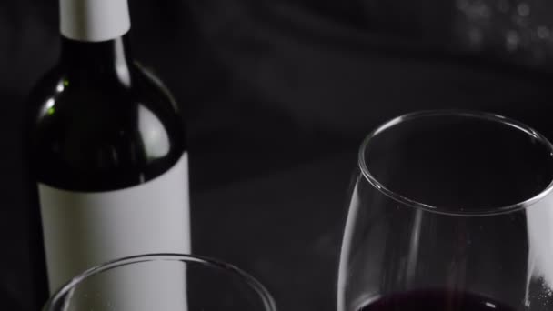 Twee Glazen Rode Wijn Een Fles Liggen Tafel Zwarte Achtergrond — Stockvideo
