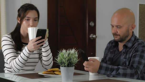 Una pareja de enamorados juntos toman té o café con galletas en la cocina — Vídeo de stock